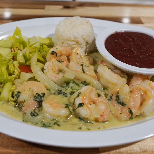 Honduran shrimp in green sauce with rice, salad, and a side of red sauce on a white plate.